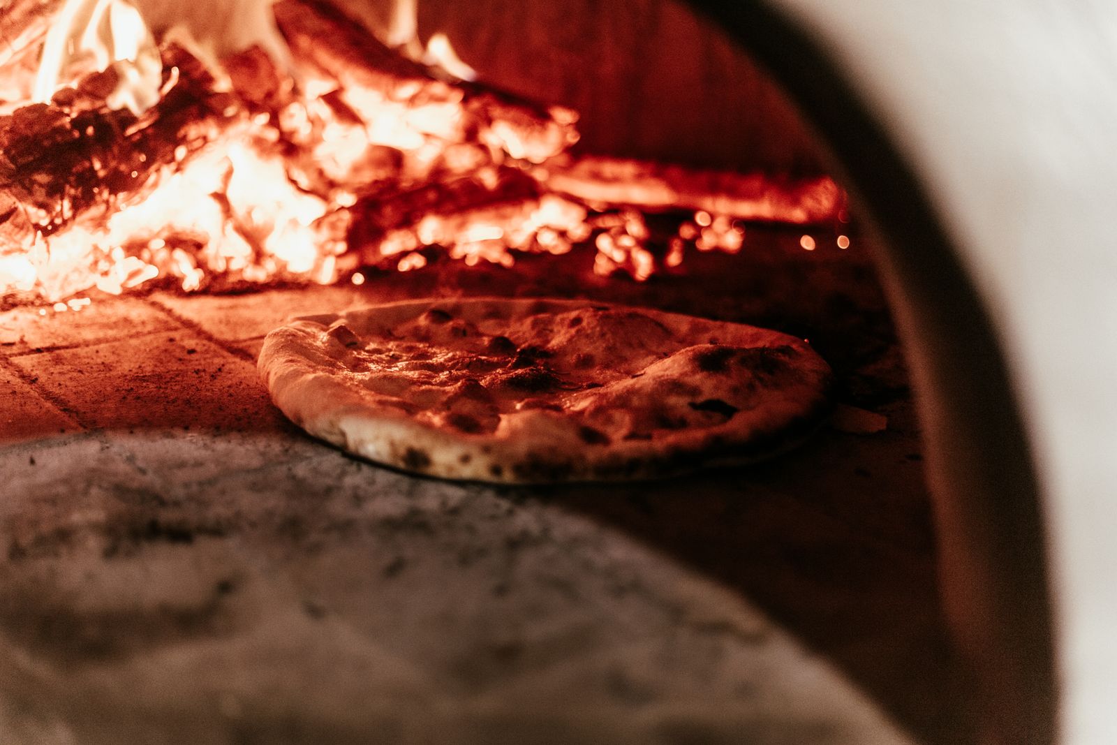 Selektives Fokusfoto einer Pizza im Ofen mit loderndem Feuer